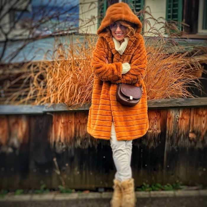 Η Μαρία Ηλιάκη με λευκό παντελόνι και faux fur coat σε κεραμιδί απόχρωση.
