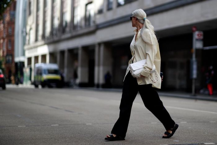 Ένα oversized πουκάμισο σε ουδέτερο χρώμα φορεμένο πάνω από ένα μαύρο παντελόνι